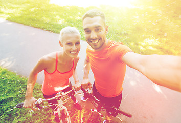 Image showing couple with bicycle taking selfie outdoors