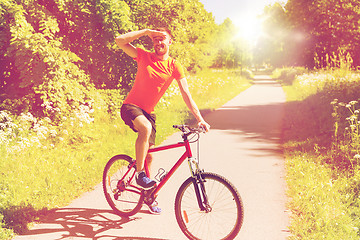 Image showing happy young man riding bicycle outdoors