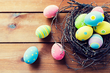 Image showing close up of colored easter eggs in nest on wood