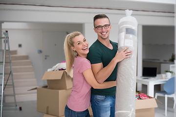 Image showing couple carrying a carpet moving in to new home