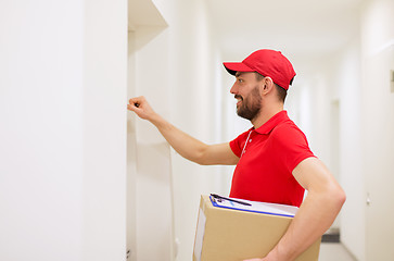 Image showing delivery man with parcel box knocking on door