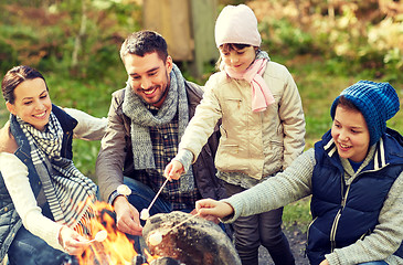 Image showing happy family roasting marshmallow over campfire