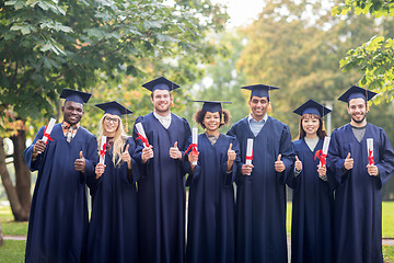 Image showing happy students with diplomas showing thumbs up