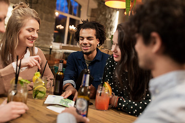 Image showing friends with drinks, money and bill at bar