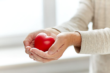 Image showing close up of senior man with red heart in hands