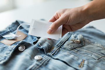 Image showing close up of hand holding price tag of denim jacket