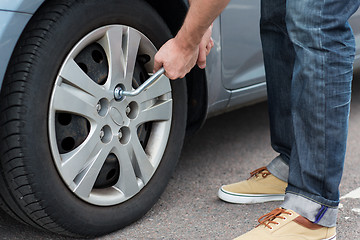 Image showing close up of man with wrench changing car tire