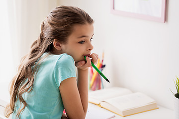 Image showing bored girl with book and pen at home