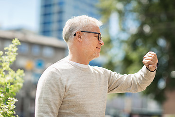 Image showing senior man checking time on his wristwatch