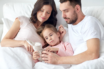 Image showing happy child with toy and parents in bed at home