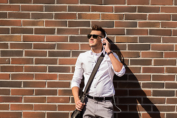 Image showing young man in headphones with bag over brickwall