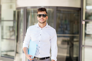 Image showing young man with business file on city street