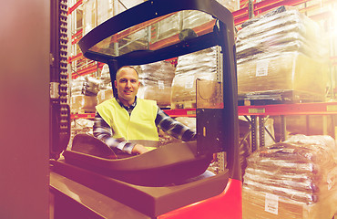 Image showing smiling man operating forklift loader at warehouse