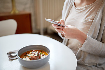 Image showing woman with smartphone and pumpkin soup at cafe