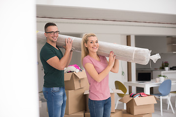 Image showing couple carrying a carpet moving in to new home