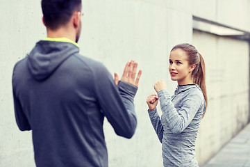 Image showing happy woman with coach working out strike outdoors