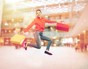 Image showing smiling young woman with shopping bags jumping