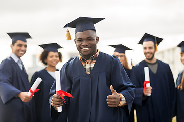 Image showing happy students with diplomas showing thumbs up