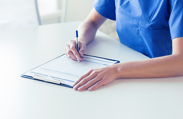 Image showing close up of doctor or nurse writing to clipboard