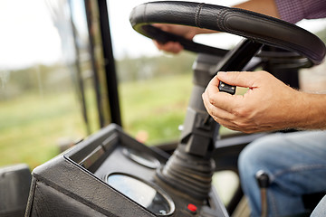 Image showing senior man driving tractor at farm