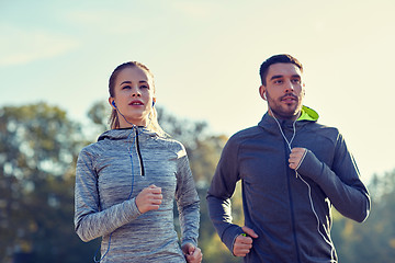 Image showing happy couple with earphones running outdoors