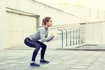 Image showing woman doing squats and exercising outdoors