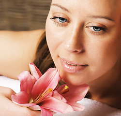 Image showing young pretty woman in spa salon with manicure and lily flower close up smiling