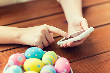 Image showing close up of hands with easter eggs and smartphone