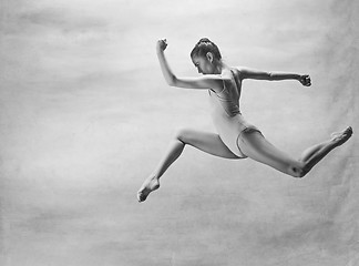 Image showing Young beautiful modern style dancer jumping on a studio background