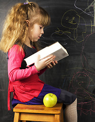 Image showing portrait of cute little girl with book and green apple near blac