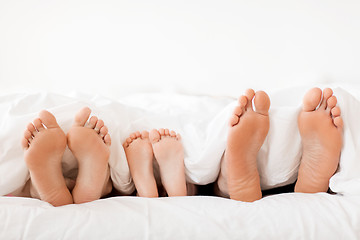 Image showing bare soles of happy family feet in bed at home