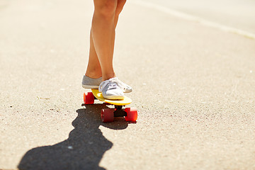 Image showing legs of young woman riding skateboard on road
