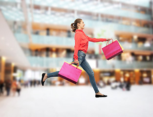 Image showing smiling young woman with shopping bags running