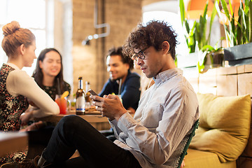 Image showing man with smartphone and friends at restaurant