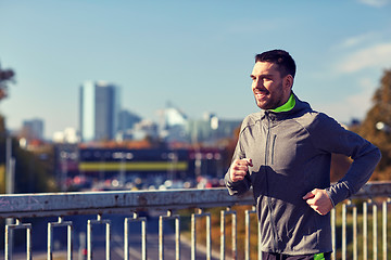 Image showing happy young man running over city bridge