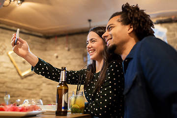 Image showing happy couple taking selfie at cafe or bar