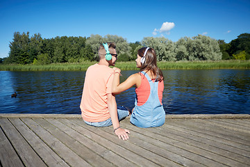 Image showing teenage couple with headphones on river berth