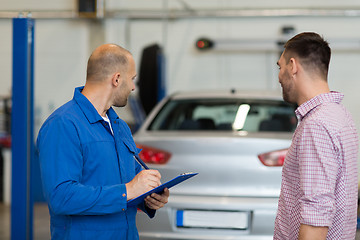 Image showing auto mechanic with clipboard and man at car shop