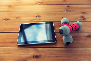 Image showing close up of dumbbells and tablet pc on wood