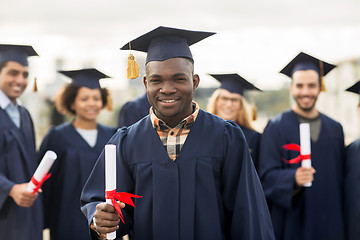 Image showing happy students in mortar boards with diplomas