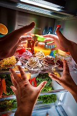 Image showing Human hands reaching for sweet cake at night in the open refrige