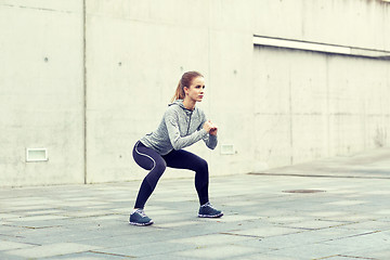 Image showing woman doing squats and exercising outdoors