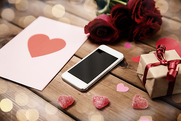 Image showing close up of smartphone, gift, red roses and hearts