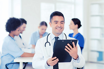 Image showing happy doctor with clipboard over medical team