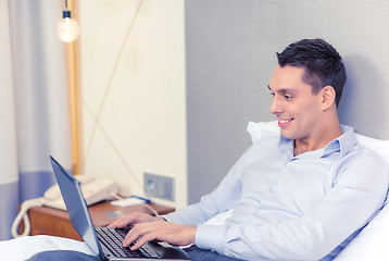 Image showing happy businesswoman with laptop in hotel room