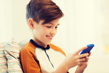 Image showing boy with smartphone texting or playing at home