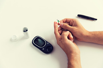 Image showing close up of man checking blood sugar by glucometer