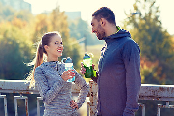 Image showing smiling couple with bottles of water outdoors