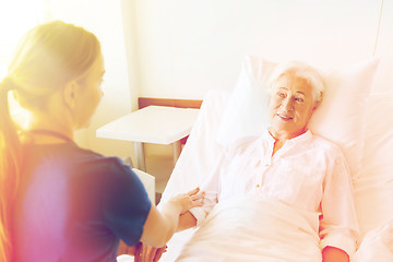 Image showing doctor or nurse visiting senior woman at hospital