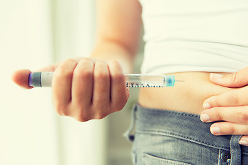 Image showing close up of hands making injection by insulin pen